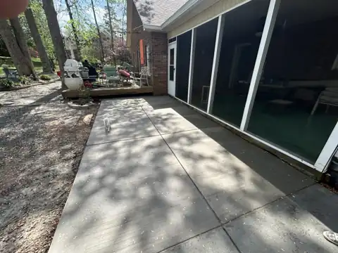 Concrete patio beside a screened porch